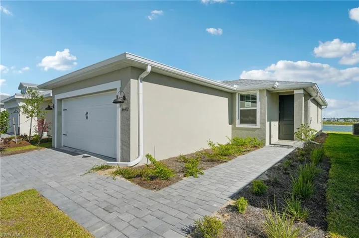 View of side of home with a garage, stucco siding, and decorative driveway