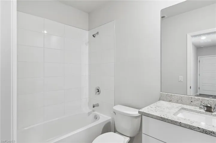 Bathroom with toilet, vanity, and  shower combination