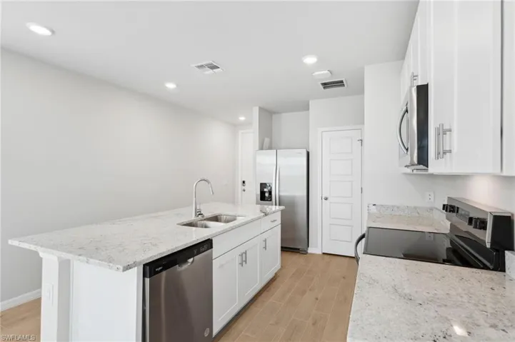 Kitchen featuring light wood-type flooring, appliances with stainless steel finishes, a sink, and visible vents