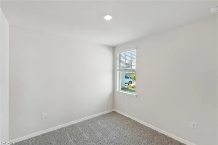 Carpeted spare room with baseboards and recessed lighting