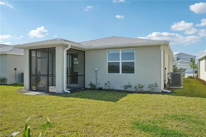 Back of house featuring a yard, stucco siding, cooling unit, and a sunroom