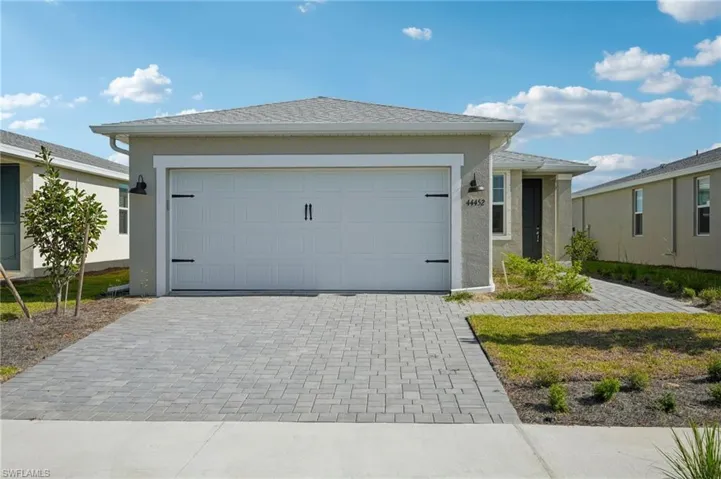 View of front of house featuring an attached garage, decorative driveway, and stucco siding