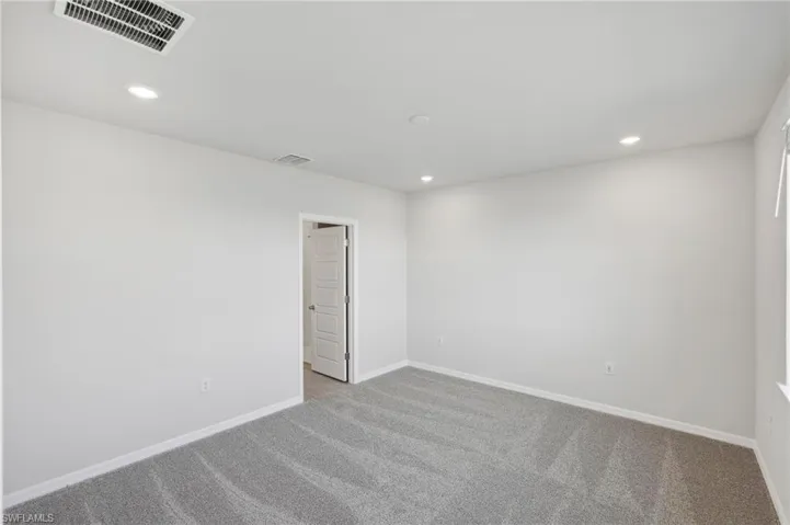 Carpeted spare room featuring baseboards, visible vents, and recessed lighting