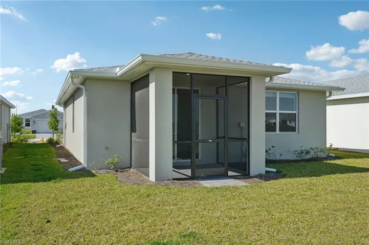 Rear view of property featuring a yard, a shingled roof, a sunroom, and stucco siding