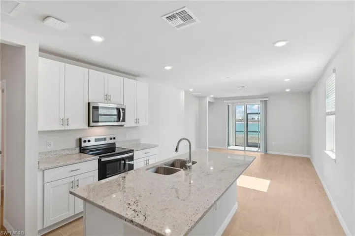 Kitchen with appliances with stainless steel finishes, a sink, white cabinetry, and visible vents