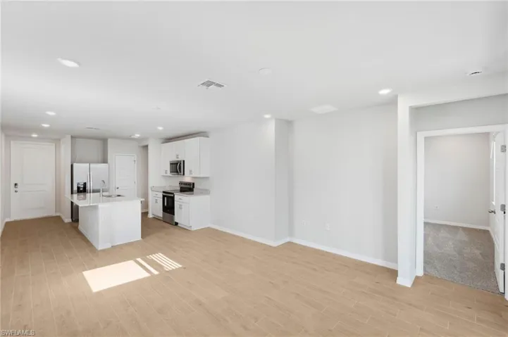 Unfurnished living room featuring visible vents, baseboards, a sink, light wood-type flooring, and recessed lighting