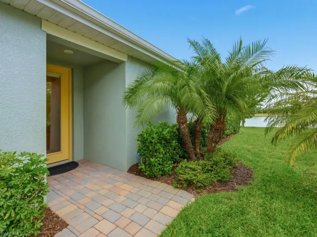 Property entrance with a lawn, stucco siding, impact front door