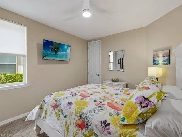 Guest Bedroom split plan with carpet and a ceiling fan with light furniture conveys including night stands, and two lamps, tv
