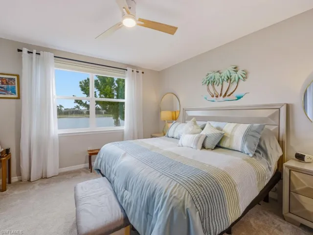 Carpeted bedroom with a water view, a ceiling fan, and vaulted ceiling