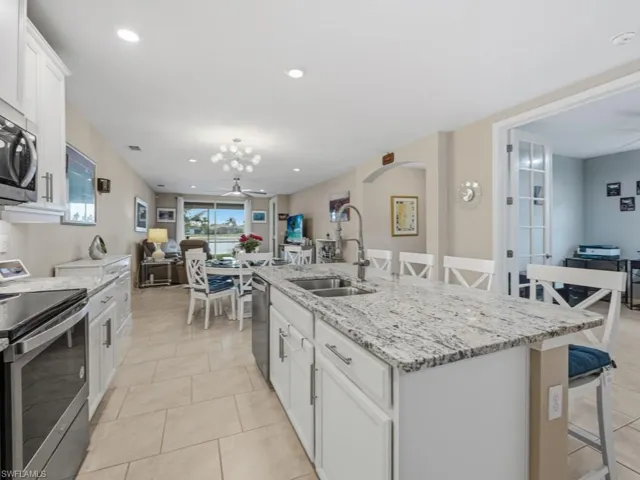 Kitchen featuring white cabinets, a kitchen breakfast bar, stainless steel appliances, and recessed lighting