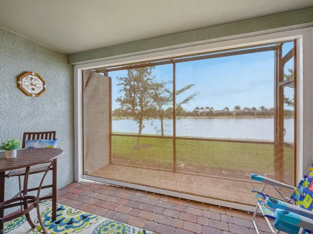 Screened lanai featuring a lake view showing hurricane shade in place to protect furniture during inclement weather