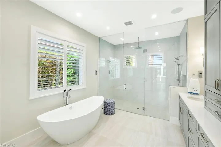 Bathroom featuring vanity, a freestanding tub, a shower stall, recessed lighting, and light tile patterned flooring