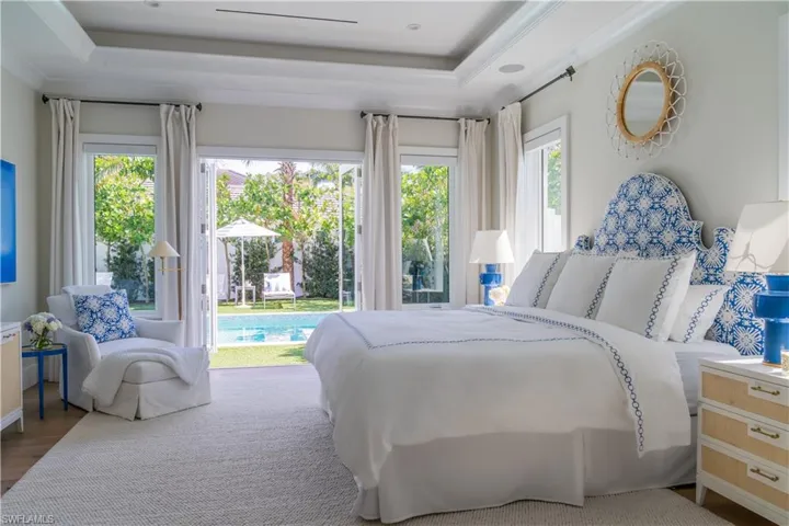 Bedroom with multiple windows, access to exterior, a raised ceiling, wood finished floors, and ornamental molding