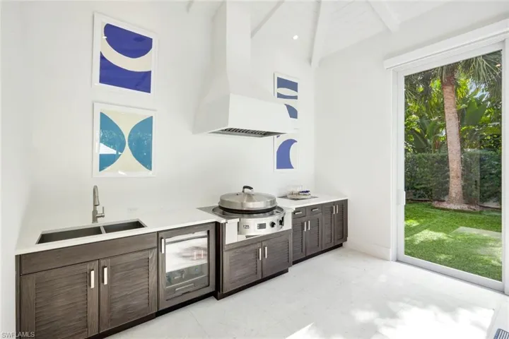 Bar area featuring dark brown cabinetry, wall chimney range hood, stainless steel cooktop, modern cabinets, and wine cooler