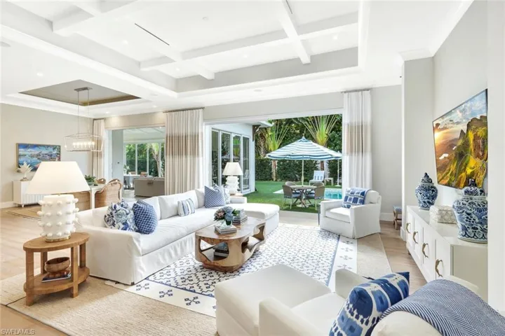 Living area with coffered ceiling, beamed ceiling, a sunroom, recessed lighting, and crown molding