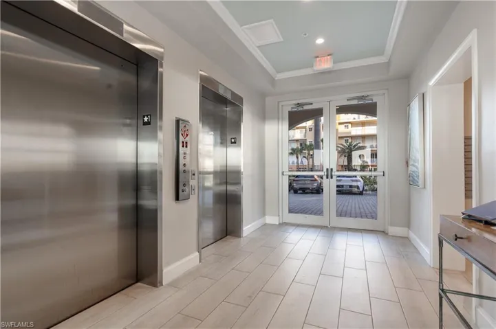 Doorway with elevator, baseboards, crown molding, and french doors