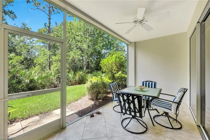 Sunroom featuring outdoor dining space, ceiling fan, and view of wooded area