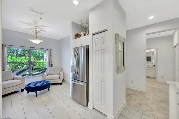 Kitchen with stainless steel refrigerator with ice dispenser, white cabinets, open floor plan, light tile patterned flooring, and recessed lighting