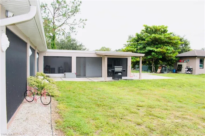 View of grassy yard featuring a sunroom