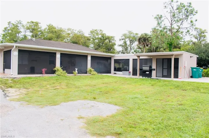 Rear view of house featuring a sunroom and a lawn