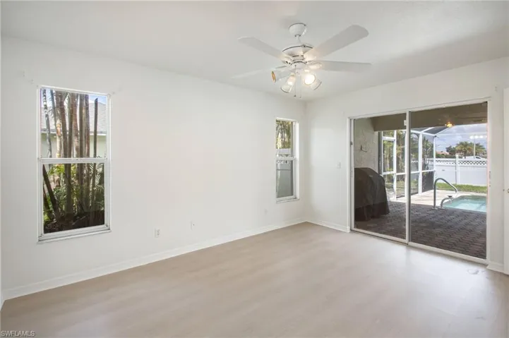 Spacious interior featuring light wood-finish flooring and a white ceiling fan with integrated lighting