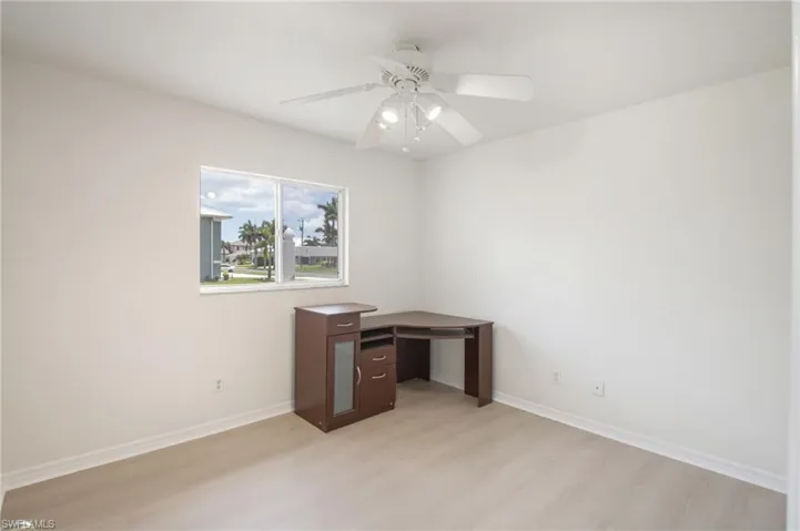 Neutral-toned room featuring a single window and wood-finish flooring