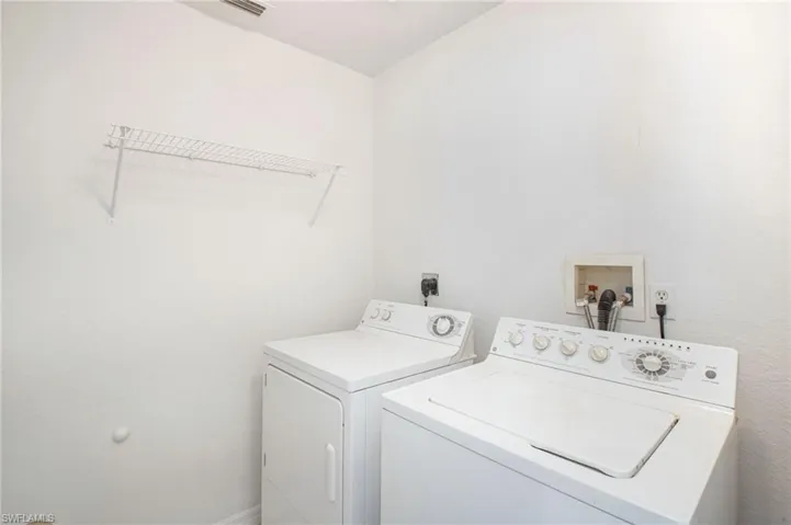 Dedicated laundry area featuring a white wire shelving unit, washing machine hookups, and electrical outlets