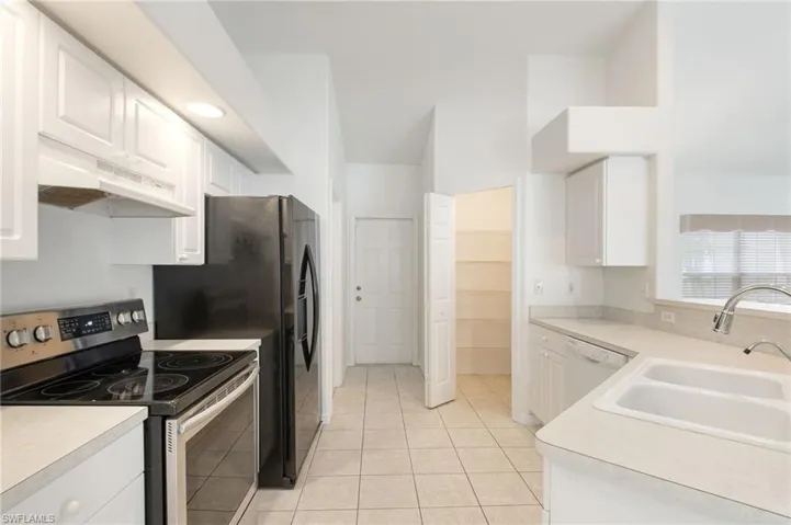 Galley kitchen featuring white cabinetry, light-toned countertops, and tile flooring