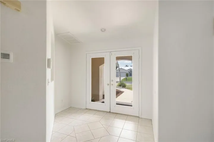 Entryway featuring double glass-panel doors, hexagonal tile flooring, recessed ceiling lighting, and a visible thermostat