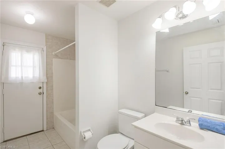 Bathroom featuring a single vanity with an integrated sink, a large wall-mounted mirror, and a full-size bathtub with a shower kit