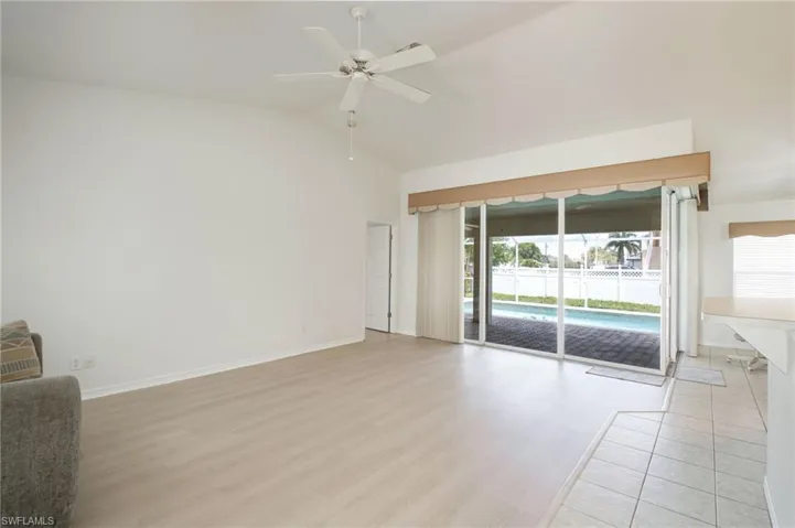Spacious living area featuring light wood-finish flooring, vaulted ceilings, and a ceiling fan
