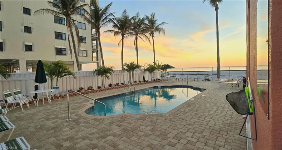 Community pool with a patio area and a beach view