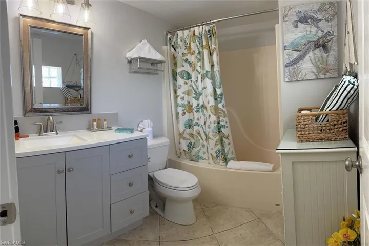 Full bath with vanity, shower tub/ bath combination with curtain, and light tile patterned floors