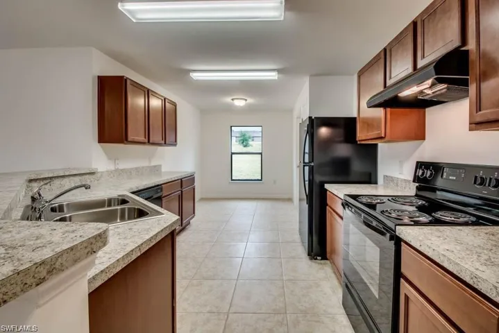 Kitchen featuring black appliances, light tile patterned floors, and sink