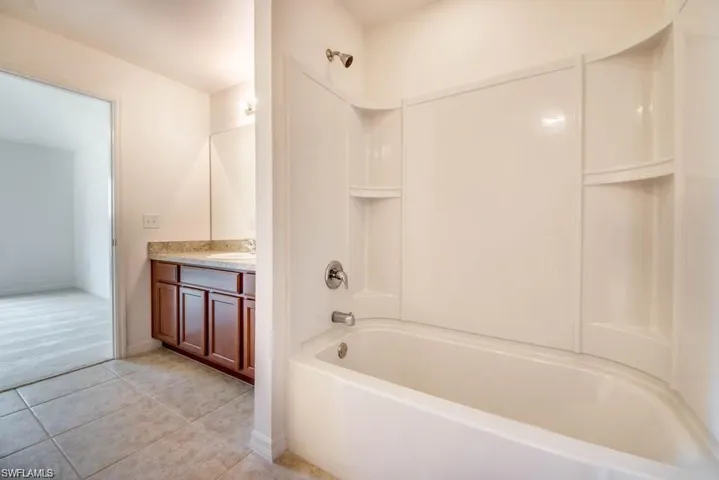 Bathroom featuring vanity, bathtub / shower combination, and tile patterned floors