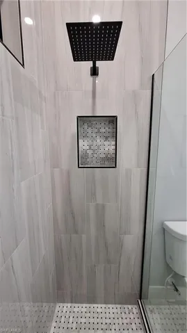Bathroom featuring tiled shower and toilet