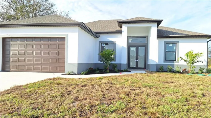 Prairie-style home with a garage, stucco siding, concrete driveway, and a front yard