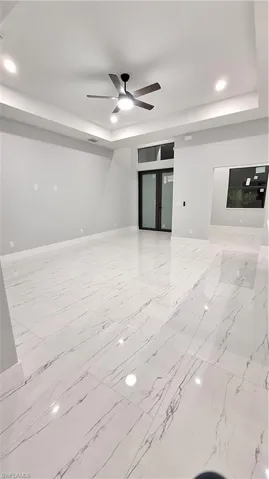 Unfurnished living room featuring ceiling fan and a raised ceiling