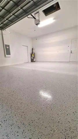 Garage with electric panel, a garage door opener, and water heater