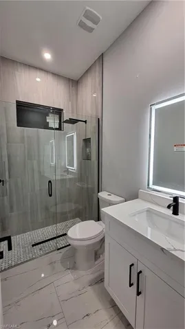 Bathroom featuring toilet, an enclosed shower, and vanity