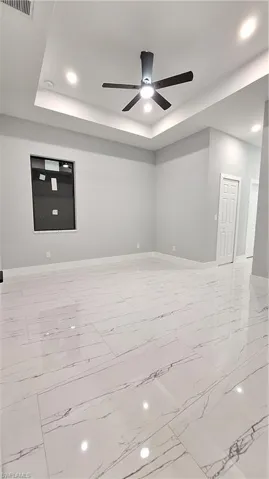 Unfurnished room with ceiling fan and a raised ceiling
