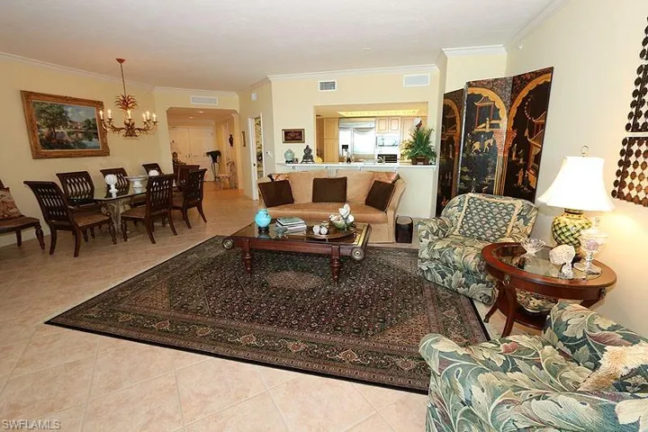 Spacious interior featuring tile flooring, a dining area with a chandelier, crown molding, and a kitchen pass-through