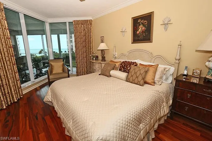 Wood-finish flooring throughout, featuring crown molding, a built-in wall sconce, and floor-to-ceiling windows with a balcony