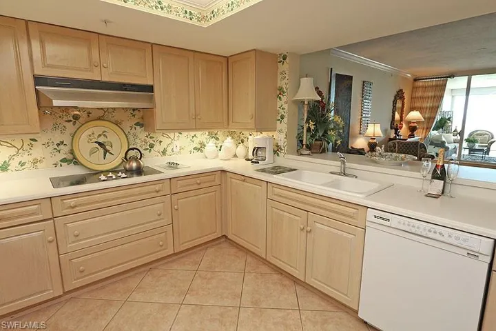 Kitchen featuring light wood cabinetry, a built-in cooktop, and a double basin sink