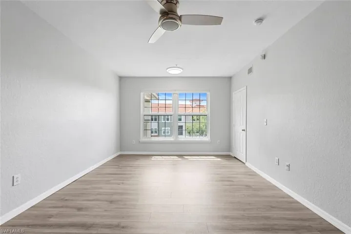 Spare room with a textured wall, baseboards, visible vents, ceiling fan, and wood finished floors