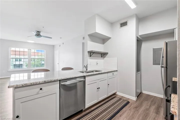 Kitchen with visible vents, a peninsula, stainless steel appliances, a sink, and open shelves