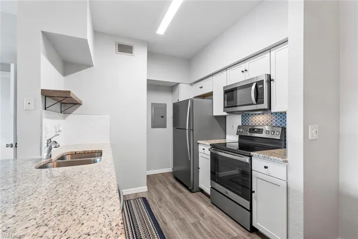 Kitchen with decorative backsplash, visible vents, stainless steel appliances, a sink, and open shelves