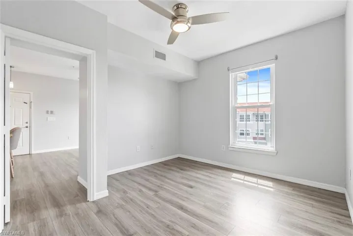 Unfurnished room with light wood finished floors, baseboards, visible vents, and ceiling fan
