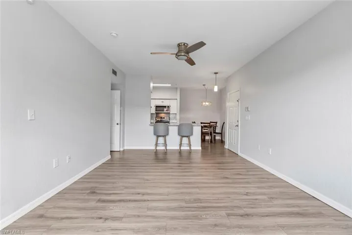 Unfurnished living room with light wood-type flooring, visible vents, baseboards, and ceiling fan