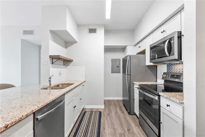 Kitchen with visible vents, electric panel, stainless steel appliances, a sink, and open shelves